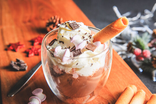 Traditional hot chocolate with whipped cream, marshmallows and chocolate shavings in a Christmas decoration