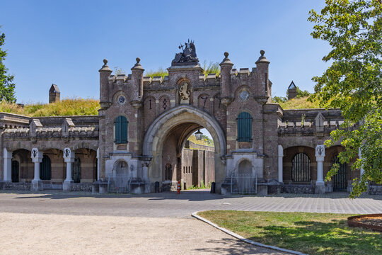 Naarden, Netherlands - The historic brick entrance gate Utrechtse Poort of the fortified town Naarden-Vesting, showing the monumental archway, stone decorations, and grassy ramparts.