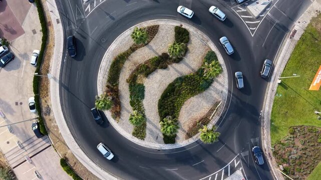 Aerial 4k drone aerial of multi lane traffic roundabout with landscaped elements and vehicles
