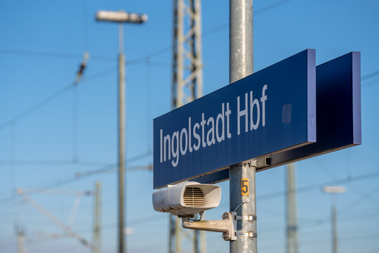 Blue station sign for Ingolstadt Hbf railway terminal with loudspeaker on metal pole under clear blue sky in Bavaria near Munich Germany