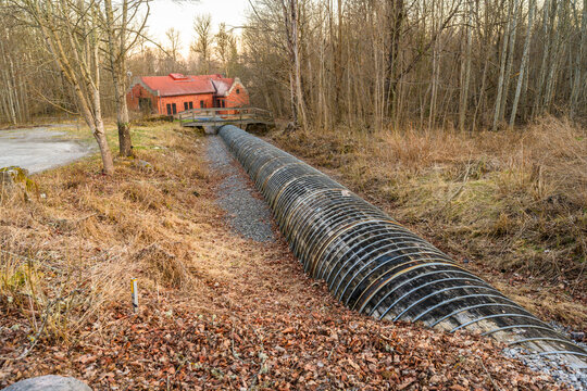 Curved industrial pipeline through dry grass and woodland landscape in countryside.
