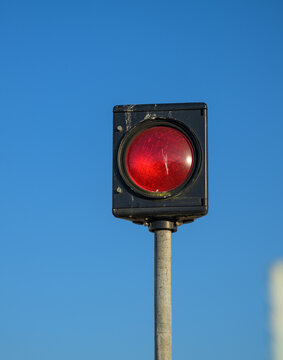 Red signal light glowing on pole against clear blue sky.