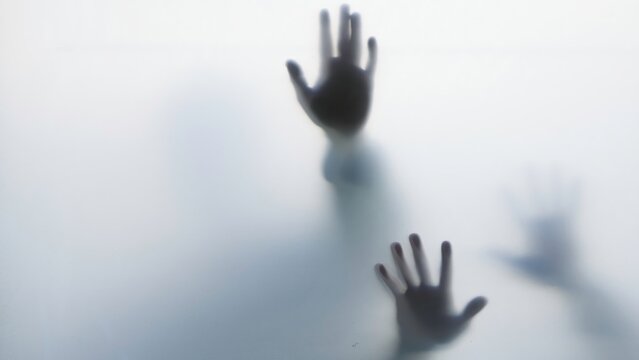 Dark hand silhouettes pressed against frosted glass