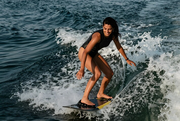 Fototapeta premium Young woman wakeboarding on ocean wave