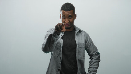 Fototapeta premium Man pointing finger to camera with hand near neck, wearing black shirt in studio portrait; confidence direct challenge.