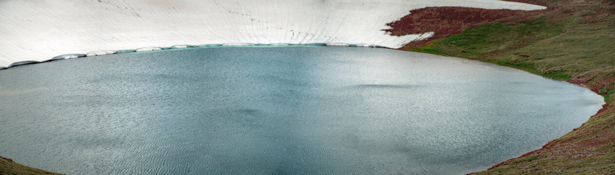 High Altitude Crater Lake with Melting Snow Shelf and Turquoise Water Edge