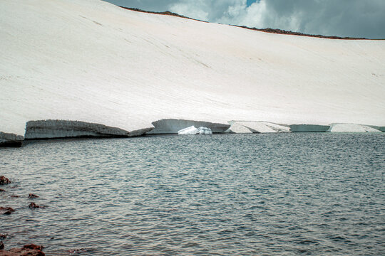 High Altitude Crater Lake with Melting Snow Shelf and Turquoise Water Edge