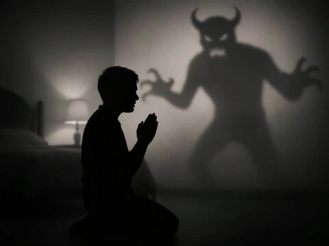 Man praying in darkness facing anxiety fear and demon shadow, psychological mental health struggle, inner turmoil and supernatural nightmare, stress and suffering concept
