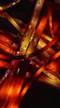 Yellow and orange lamps lighting the highways and freeways in the interchange of metropolis. Dallas roads at night from top view. Vertical video