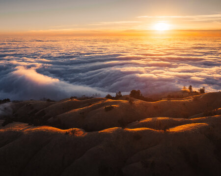 Sunset above a sea of clouds illuminating rolling hills in Big Sur, California