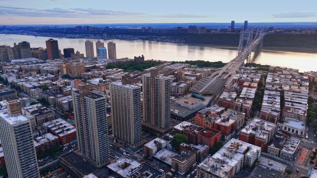 Footage over the buildings of the Washington Heights neighborhood in Upper Manhattan, New York City. The George Washington Bridge at sunset in the backdrop.