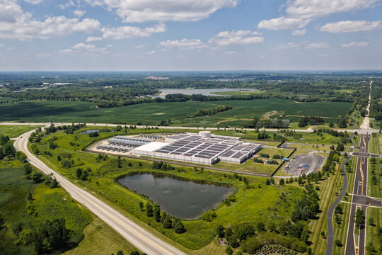 Aerial view of the data center complex, large AI center structure surrounded by pond and green countryside areas 