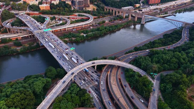Many cars move by the loops, highways and bridges at sunset. Top view on the Alexander Hamilton Bridge Interchange spanning across the Harlem River in New York City.
