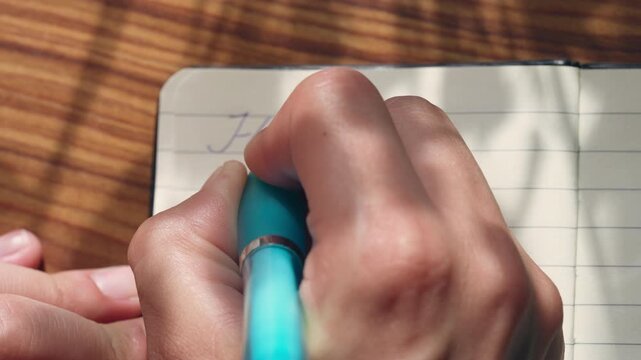 Close-Up of Person Writing the Word "Hope" in a Notebook with a Fountain Pen