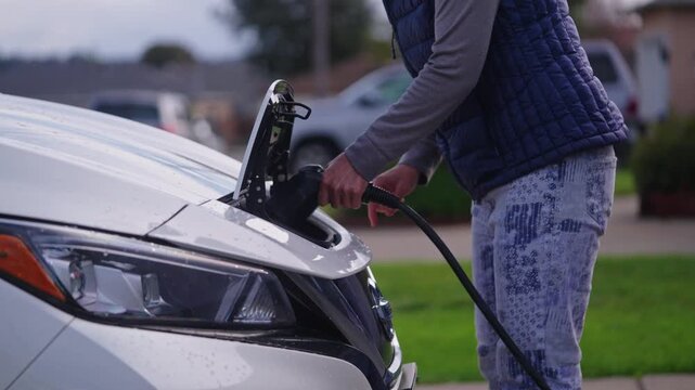 Japanese Woman Charging Electric Vehicle at Home in Residential Neighborhood
