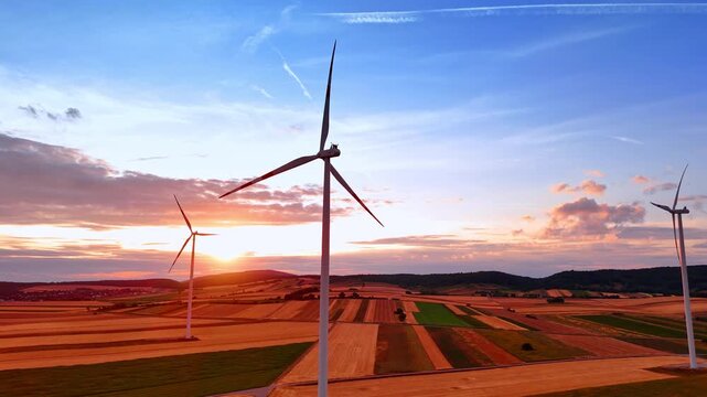 Modern turbines rotate in the wind. Windmills produce energy in the field at sunset.