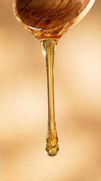 Wooden spoon dripping honey against a blurred warm background