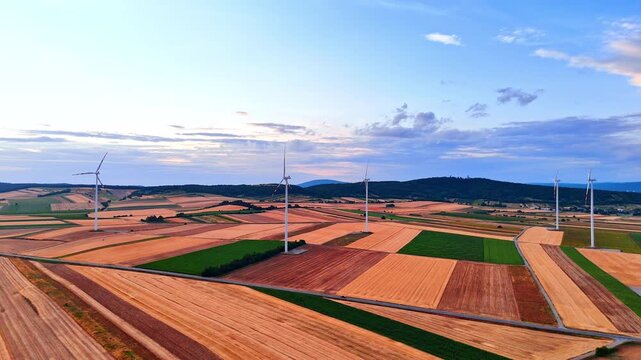 Agricultural fields with several wind turbines. Farmlands used for green energy production.