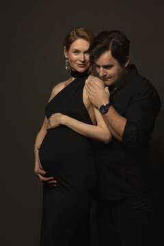 A pregnant slim girl poses with her husband in black outfits
