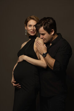 A pregnant slim girl poses with her husband in black outfits