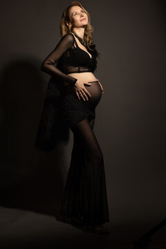 A pregnant slim girl poses with her husband in black outfits
