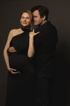 A pregnant slim girl poses with her husband in black outfits
