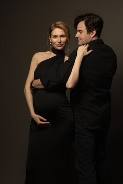 A pregnant slim girl poses with her husband in black outfits