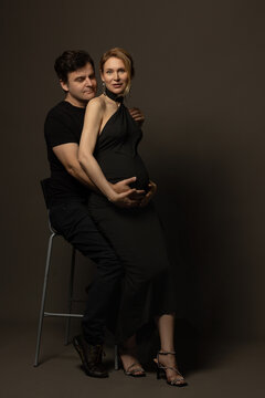 A pregnant slim girl poses with her husband in black outfits