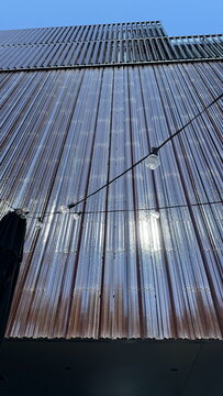 Low angle view of modern building facade with string lights under blue sky for architecture concept