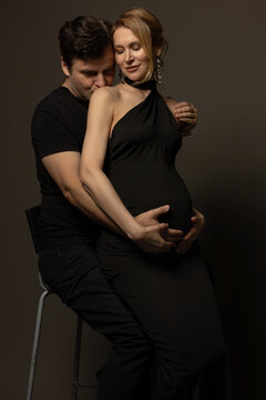 A pregnant slim girl poses with her husband in black outfits