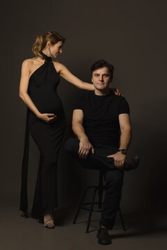 A pregnant slim girl poses with her husband in black outfits