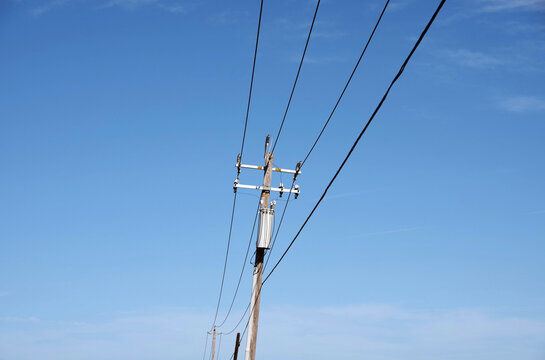 Simple rural electricity distribution pylon and power lines under blue sky