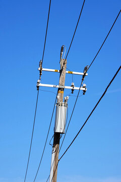 Simple rural electricity distribution pylon and power lines under blue sky
