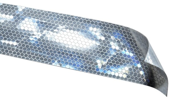 Close-up of reflective safety tape with hexagonal pattern and blue-white light reflections, used for vehicle visibility and protective applications.