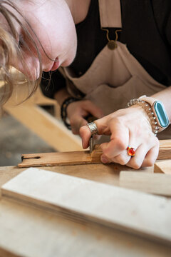 Woman carpenter working on old wooden frame with chisel, carving wood layers with instrument, craftswoman restoring vintage window frame, using special tools at workbench, handmade art and craft.