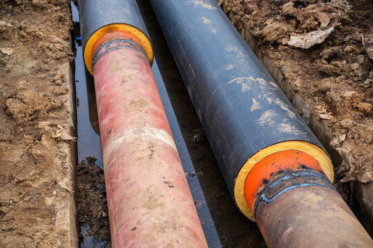 Heating pipes in excavated trench after repair and maintenance of underground utility network, concept of district heating service and infrastructure restoration