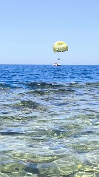 Parasailing on a yellow parachute over the azure sea