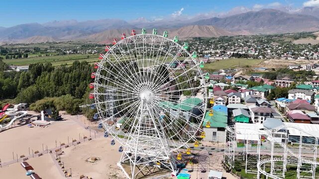 Ferris wheel by Issyk-Kul Lake with scenic mountains in the background, a popular tourist spot.