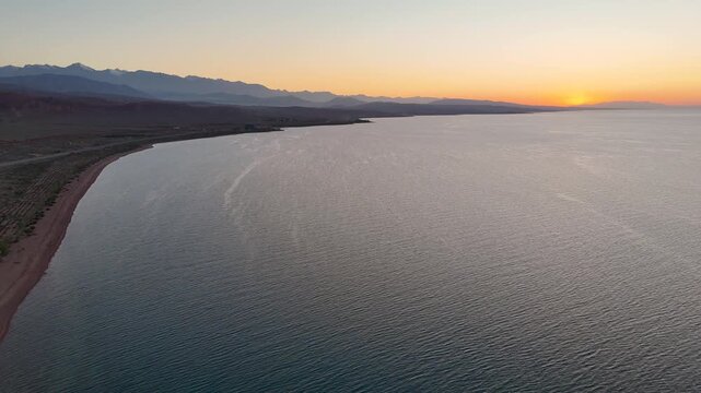 Stunning drone view of Issyk-Kul Lake at sunset, showcasing golden skies