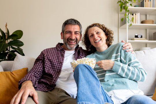 Happy couple enjoying leisure time eating popcorn at home
