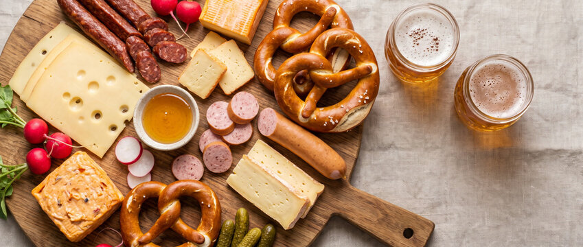 Flat lay of Oktoberfest cheese and charcuterie board with sausages and beer