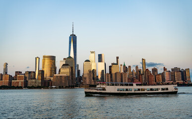 Naklejka premium New York city at sunset. Ship tour of NYC. NY urban city architecture. Midtown Manhattan and Hudson river. Ferry touristic cityscape. New York downtown. Manhattan skyline on touristic ferry
