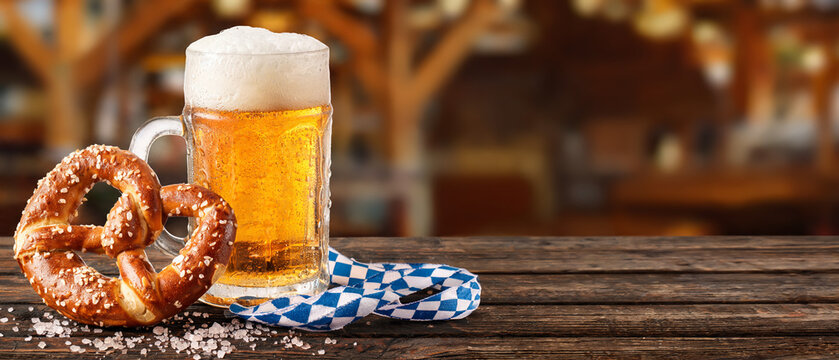 Bavarian soft pretzel and glass of draft beer on wooden table, Oktoberfest banner copy space