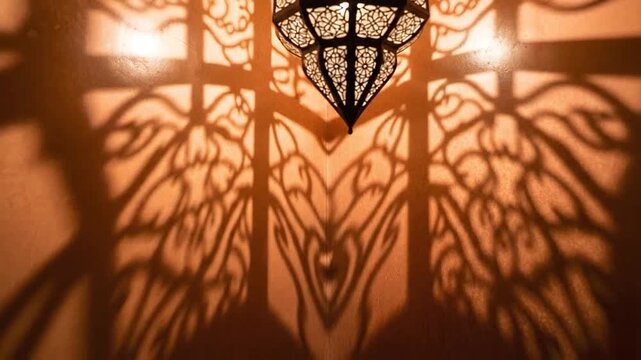 An ornate metal lantern casts intricate floral shadows upon a warm textured wall surface