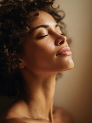 Fototapeta premium A relaxed young woman with curly hair and closed eyes enjoys a peaceful moment with soft natural lighting highlighting her serene expression and smooth skin