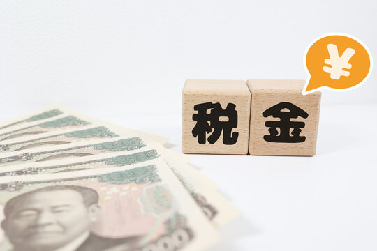 税金と1万円札。日本円記号と柱の文字。白背景。