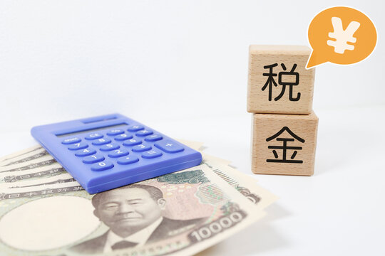 税金と日本円。電卓と1万円札。家計管理のイメージ