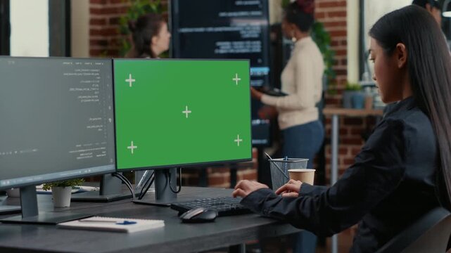 Asian programmer writes programming code beside a green screen chroma key mockup, creating replaceable display space for app interface work