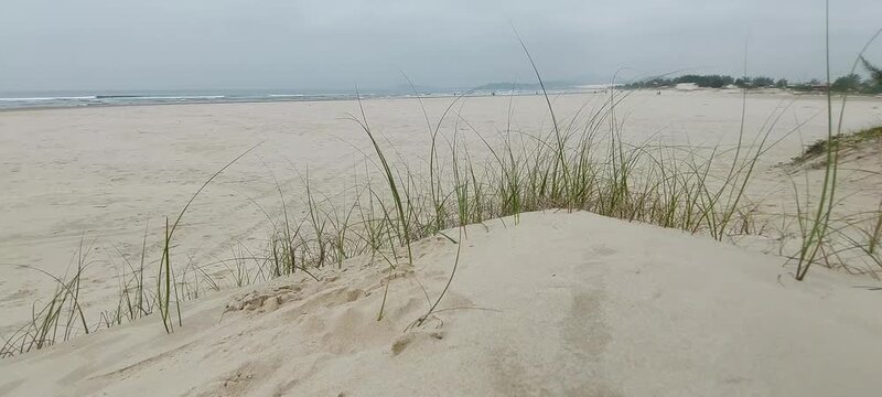 Cloudy beach dune view with sea and hills at barra da ibiraquera