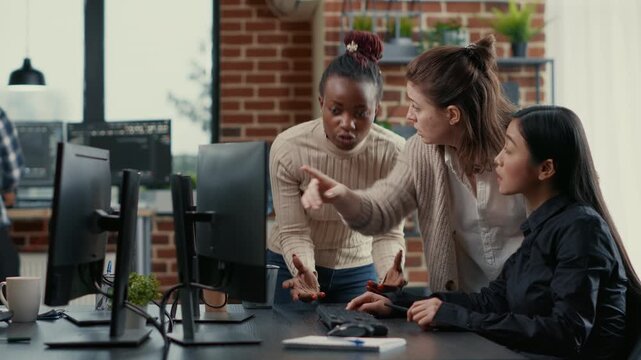 Mixed software development team discusses software library structure at a workstation, using running code displays to organize project ideas and technical feedback